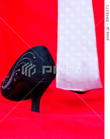 Black female shoes and necktie on red background 9948371