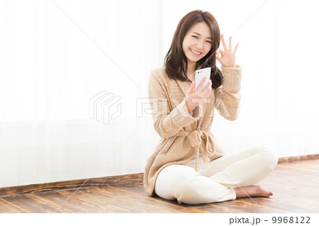 部屋でスマートフォンを見る女性 9968122