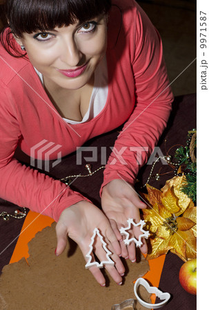Beautiful young woman cutting gingerbread shapes from dough Beautiful young woman cutting gingerbread shapes from dough 9971587