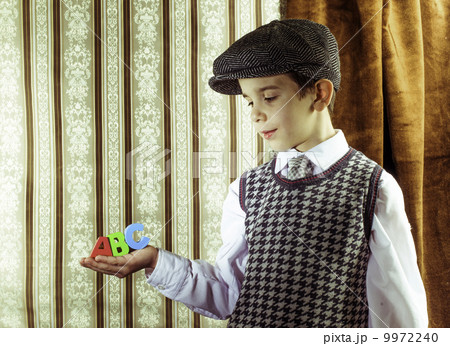 Child in vintage clothes hold letters a b c 9972240