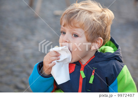 Adorable toddler eating bread outdoor 9972407