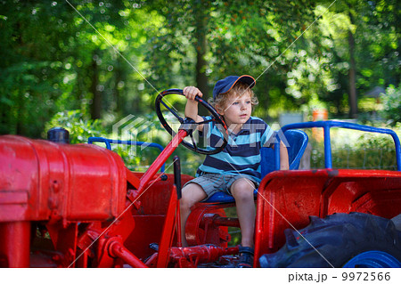 Portrait of little blond boy in tractor in summer Portrait of little blond boy in tractor in summer 9972566