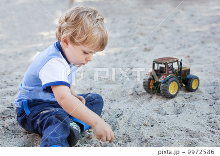 Little toddler boy playing with sand and toy 9972586