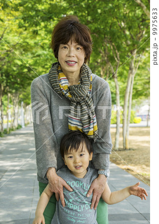 Grandmother hugging grandson in a park in an asian city on a sunny day. 9975633