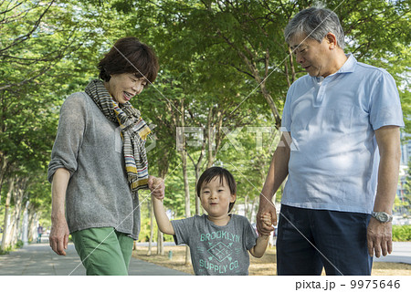 Grandparents and grandson walking in a park in an asian city on a sunny day. 9975646
