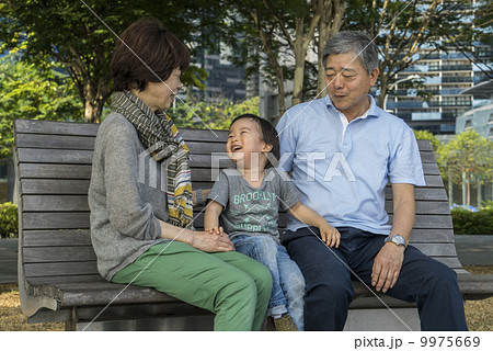 Grandparents and grandson sitting on a bench in a park in an asian city on a sunny day. Grandparents and grandson sitting on a bench in a park in an asian city on a sunny day. 9975669
