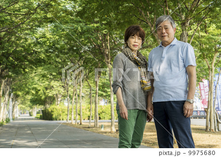 Portrait of an elderly couple traveller taking photos in a park with in an asian city on a sunny day 9975680