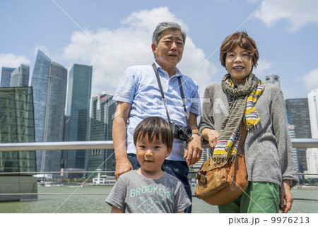 Grandparents and grandson walking in a park in an asian city on a sunny day. 9976213