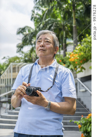 An elderly man taking photos in a park outside a tourist area. 9976228