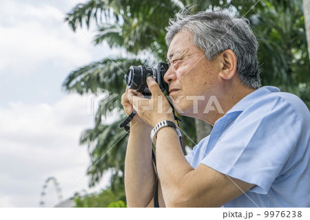 An elderly man taking photos in a park outside a tourist area. An elderly man taking photos in a park outside a tourist area. 9976238