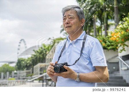 An elderly man taking photos in a park outside a tourist area. 9976241