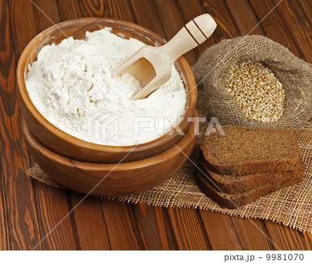 Flour in wooden bowl and wheat in burlap bag. Flour in wooden bowl and wheat in burlap bag. 9981070