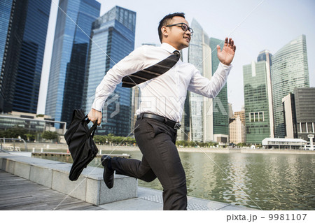 Young male malay business executive running in city 9981107