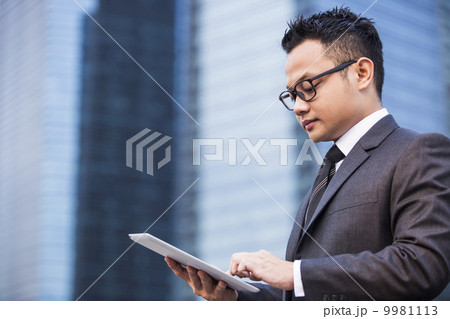 Young male malay executive using a tablet 9981113