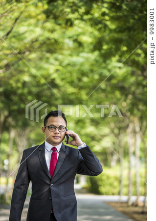 Young male malay executive talking on his smart phone 9983001
