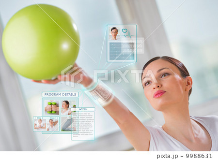 Woman doing exercise with ball wearing smart wearable device wit Woman doing exercise with ball wearing smart wearable device wit 9988631