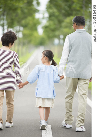 一本道で手をつなぐ祖父母と孫の後姿 一本道で手をつなぐ祖父母と孫の後姿 10016498