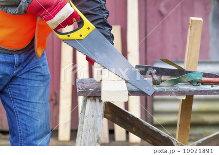 Carpenter sawing plank on to the work table 10021891