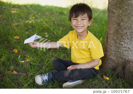 Happy boy playing with a paper plane at park Happy boy playing with a paper plane at park 10025767