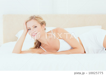 Attractive blonde lying on her bed smiling at camera Attractive blonde lying on her bed smiling at camera 10025775