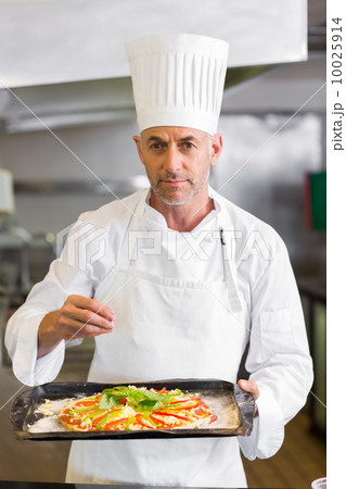 Confident chef holding cooked food in kitchen Confident chef holding cooked food in kitchen 10025914