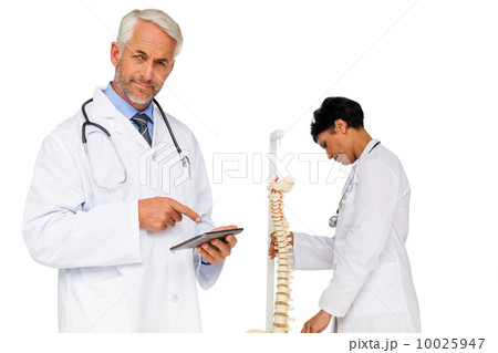 Doctor holding digital table with colleague by skeleton model 10025947