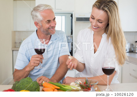 Cheerful couple making dinner together and drinking red wine 10026120