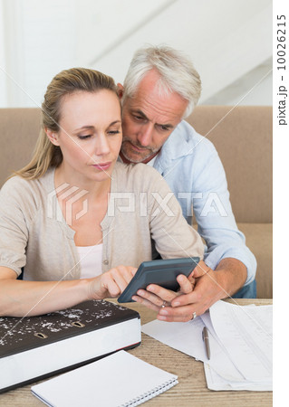 Serious couple calculating their bills at the couch Serious couple calculating their bills at the couch 10026215