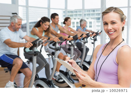Trainer with people working out at spinning class 10026971