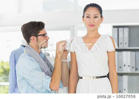 Fashion designer adjusting dress on model Fashion designer adjusting dress on model 10027056