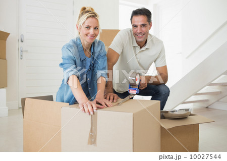 Smiling couple packing boxes in a new house 10027544