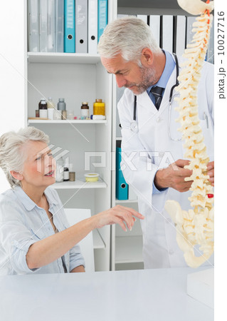 Male doctor explaining the spine to senior patient 10027716