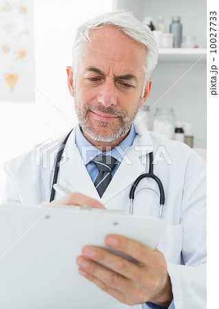 Concentrated male doctor writing reports Concentrated male doctor writing reports 10027733