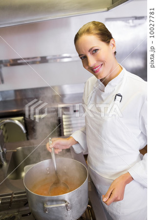 Smiling female cook preparing food in kitchen 10027781