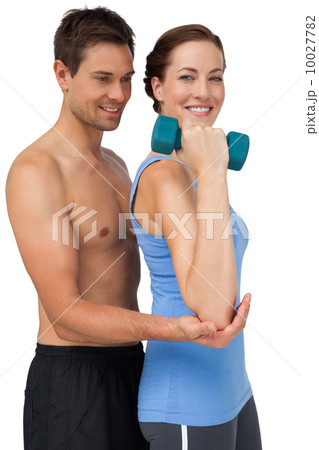 Male trainer assisting woman with dumbbell 10027782