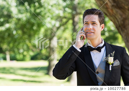 Groom using cellphone in garden 10027786