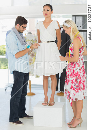 Fashion designers adjusting dress on model 10027787