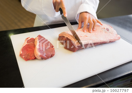 Mid section of hands cutting meat in kitchen 10027797