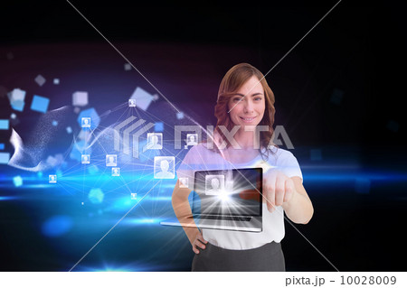 Smiling businesswoman pointing to laptop and profiles behind 10028009