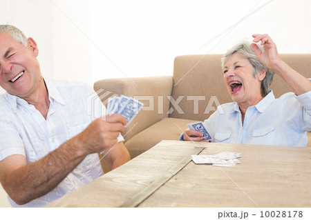 Senior couple sitting on floor playing cards Senior couple sitting on floor playing cards 10028178