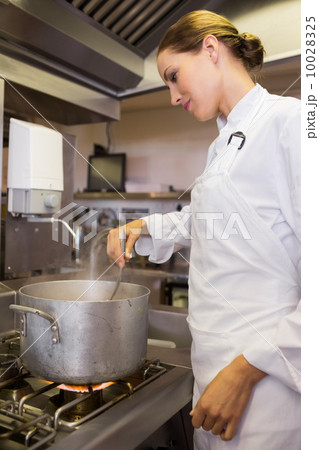 Concentrated female cook preparing food in kitchen 10028325