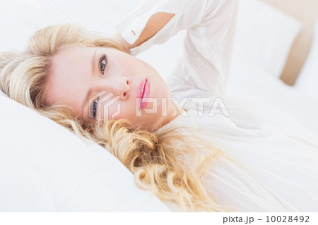 Gorgeous young woman in white shirt smiling at camera lying on b 10028492