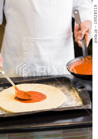 Mid section of a male chef preparing pizza Mid section of a male chef preparing pizza 10028519