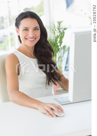 Cheerful businesswoman sitting at her desk Cheerful businesswoman sitting at her desk 10028792