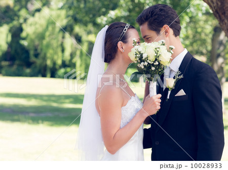 Couple kissing behind bouquet in garden Couple kissing behind bouquet in garden 10028933