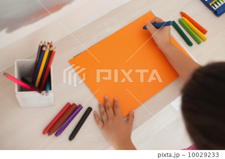 High angle of a girl drawing on orange paper at home 10029233