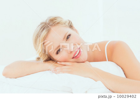 Attractive young blonde lying on her bed smiling at camera 10029402