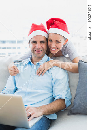 Happy couple in santa hats shopping online with laptop Happy couple in santa hats shopping online with laptop 10029627