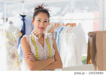 Portrait of a beautiful female fashion designer with rack of clo Portrait of a beautiful female fashion designer with rack of clo 10029980