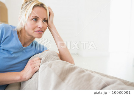 Thoughtful young woman sitting in living room Thoughtful young woman sitting in living room 10030001